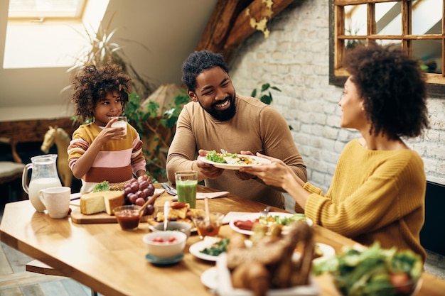 Gelukkige zwarte familie genieten van een maaltijd aan de eettafel thuis