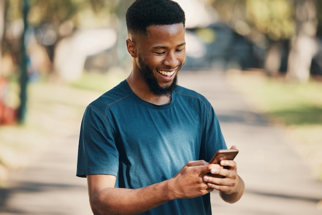 Gelukkige zwarte man en smartphone in de stad voor communicatie en buiten voor sociale media Afro-Amerikaanse mannelijke glimlach en mobiele telefoon om te chatten, online bladeren en zoeken op internet met geluk