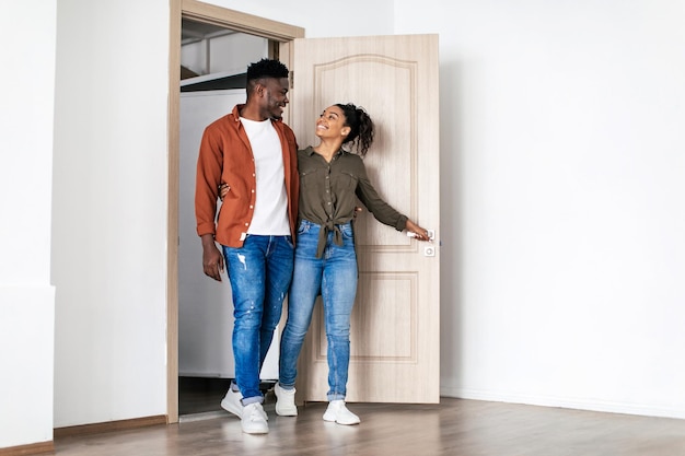 Gelukkige zwarte man en vrouw knuffelen eigen huis binnenkomen