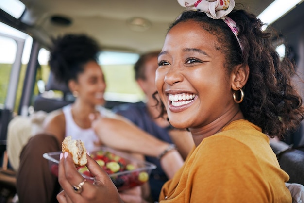 Gelukkige zwarte vrouw glimlacht en eet op roadtrip-avontuur met vrienden op reis voor zomervakantie of reis Afro-Amerikaanse vrouw glimlacht en geniet van een gezonde maaltijd voor vakantiereizen