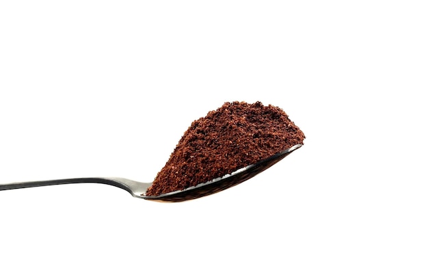 Gemaald koffiepoeder in een theelepeltje van roestvrij staal geïsoleerd op een witte achtergrond