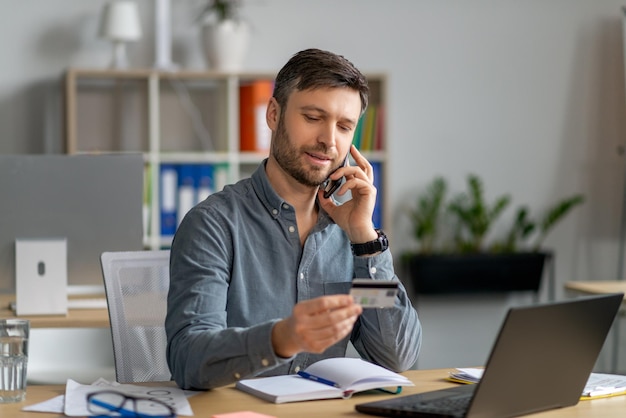 Gemakkelijk betalingen concept volwassen zakenman werknemer met creditcard en praten op mobiele telefoon met