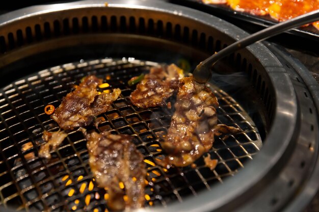 Foto gemarineerd wagyu-rundvlees dat op de gegrilde plaat sist bij een selectieve focus van een koreaans bbq-restaurant