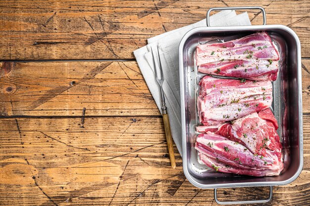 Gemarineerde lamsschenkels met kruiden, specerijen en tijm Schapenvlees klaar om te koken Houten achtergrond Bovenaanzicht Kopieer ruimte