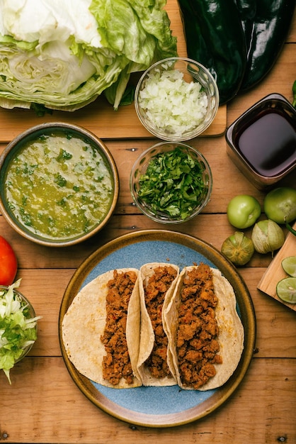 Gemarineerde rundvleestaco's kom met salsa verde en groenten op een houten tafel Tacos de adobada