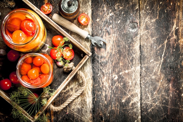 Gemarineerde tomaten met kruiden in een oud bakje. Op een houten achtergrond.