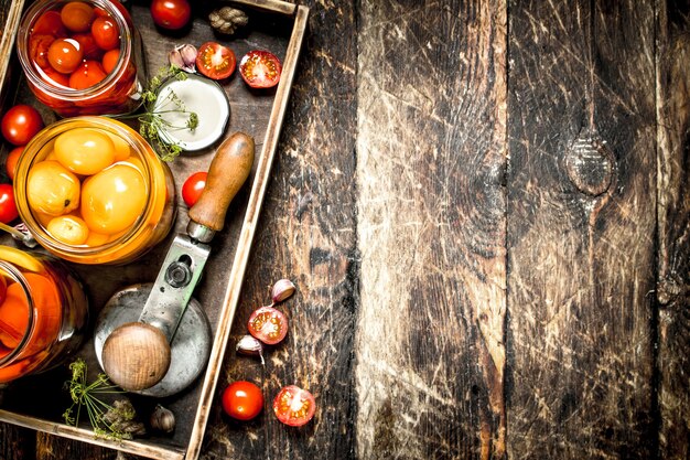 Gemarineerde tomaten met kruiden in een oude bak op een houten tafel.