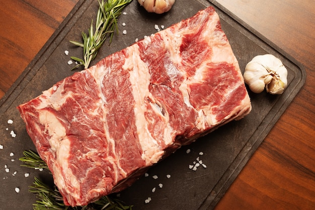 Gemarmerd rundvlees van topkwaliteit. Een stuk ligt op een snijplank met rozemarijn en knoflook
