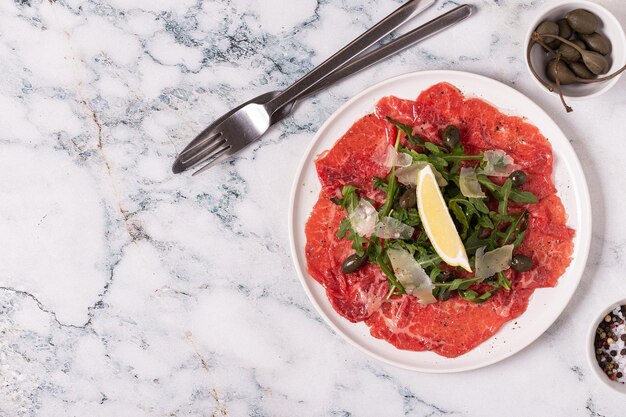 Gemarmerde rundercarpaccio met rucola kappertjes citroen en Parmezaanse kaas