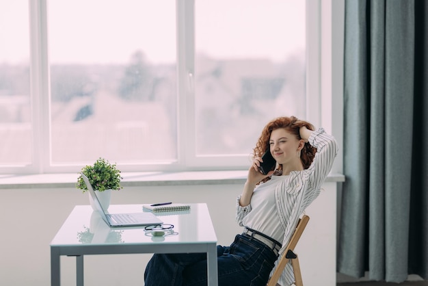 Gember jonge vrouw die op laptop typt terwijl ze thuis aan een bureau zit