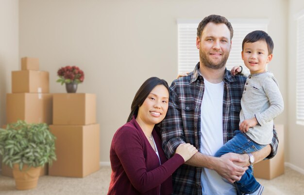 Foto gemengd ras chinese en blanke ouders en kind in een lege kamer met verhuisdozen