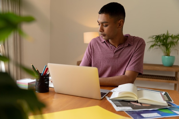 Gemengd ras man zittend aan tafel met behulp van laptop en leren