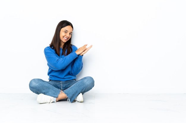 gemengd ras vrouw applaudisseren zittend op de vloer