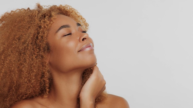 Gemengd ras zwart blond model met krullend haar gelukkig lachend raakt haar huid