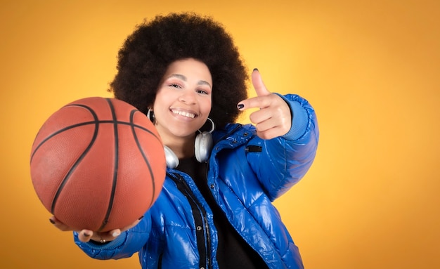 Gemengde afro-vrouw, met blauwe jas, vrijetijdskleding, met basketbal