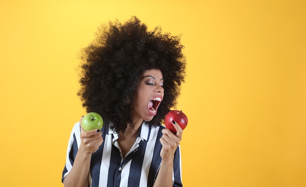 Gemengde afrovrouw, met twee rode en groene appels, gezond leven