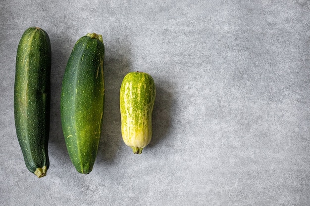 Gemengde gele, witte, gestripte en groene courgette's op een grijze betonnen ondergrond