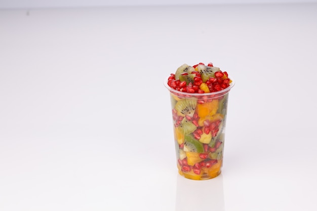 Gemengde gesneden vruchten gerangschikt in een transparant glas met witte achtergrond, geïsoleerd.
