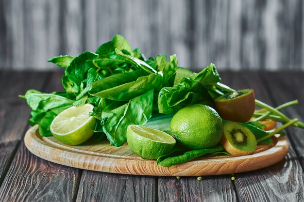 Gemengde groene smoothie met ingrediënten op het stenen bord, houten tafel selectieve aandacht