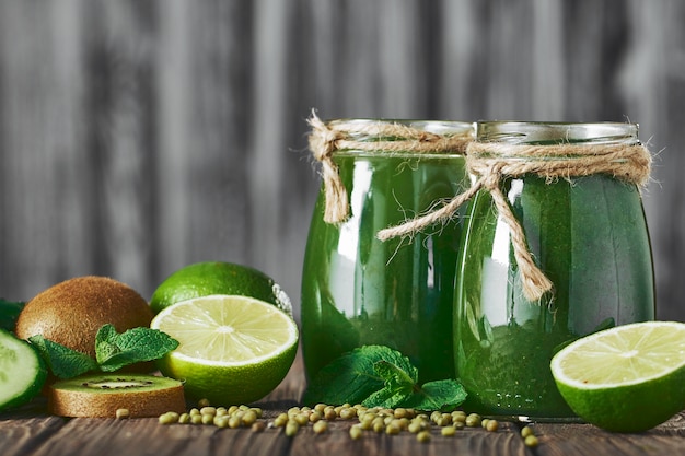 Gemengde groene smoothie met ingrediënten op het stenen bord, houten tafel selectieve aandacht