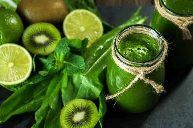 Gemengde groene smoothie met ingrediënten op het stenen bord, houten tafel