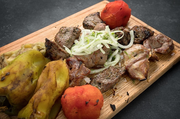 Gemengde kebab met gebakken groenten op een houten bord