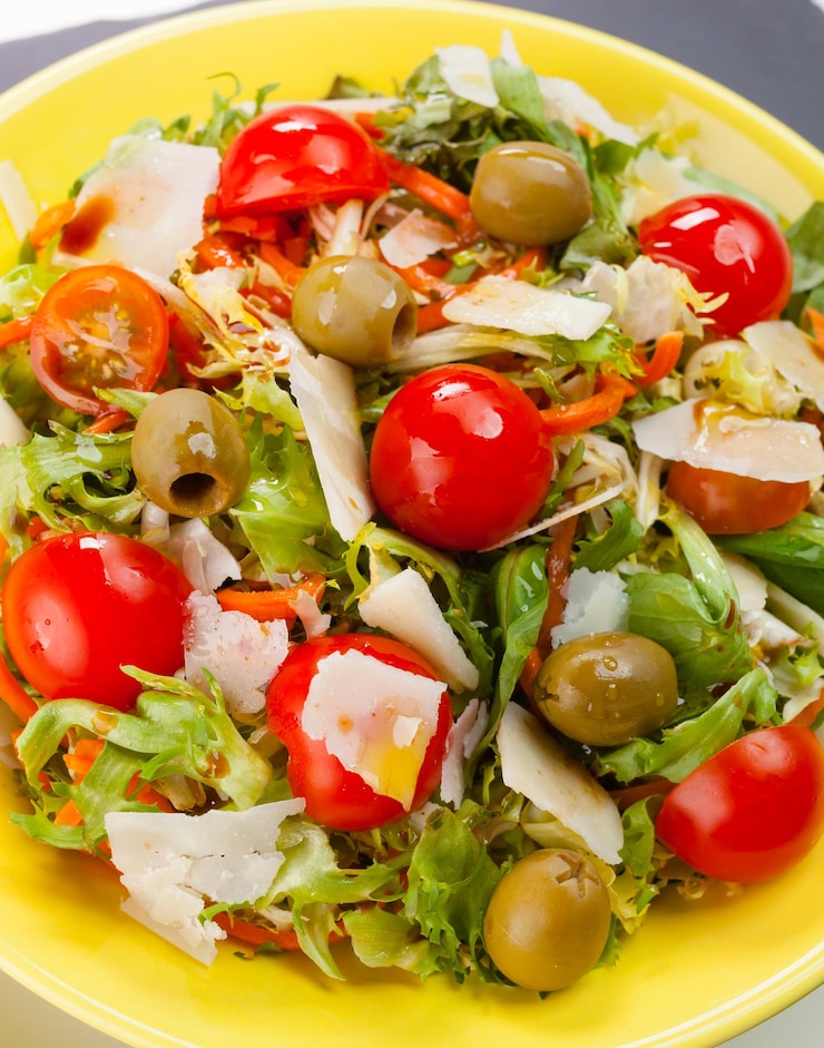 Foto gemengde salade met olijven kaas en tomaten op zwarte leisteen