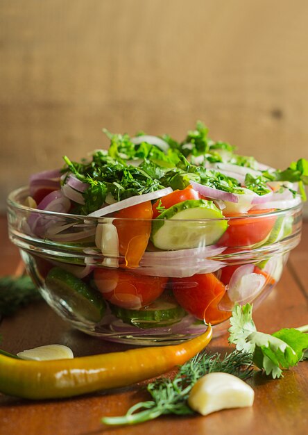 Gemengde salade met verse groenten: tomaten, chili, komkommer, rode ui, knoflook, dille, peterselie.