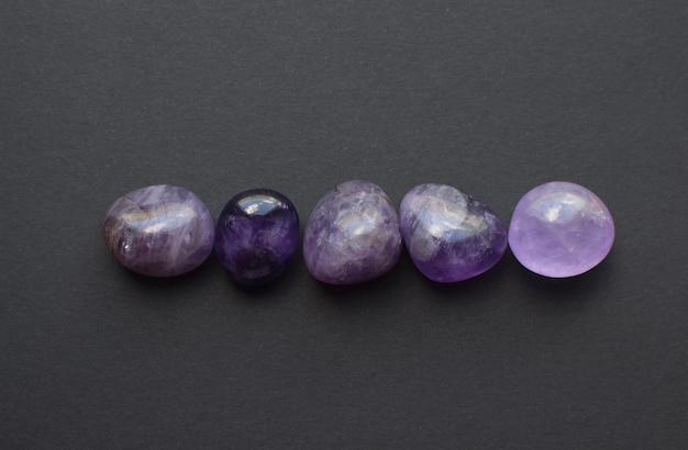 Gemstone minerals on a black background Round tumbling minerals of amethyst and amethyst crystal