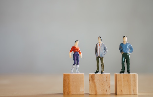 Photo gender equality concept, miniature female figurine stand same level as male figurines