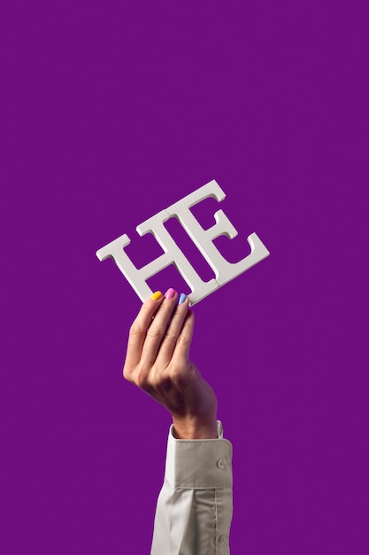 Photo gender fluid person holding a pronoun isolated on purple