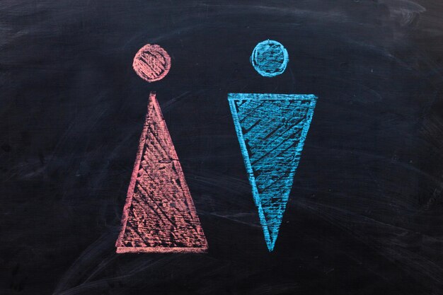 Gender icons of men and women drawn in blue and pink chalk on the blackboard