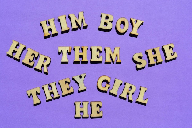 Gender pronouns They Them Him He She Her Boy Girl words in wooden alphabet letters isolated on purple background