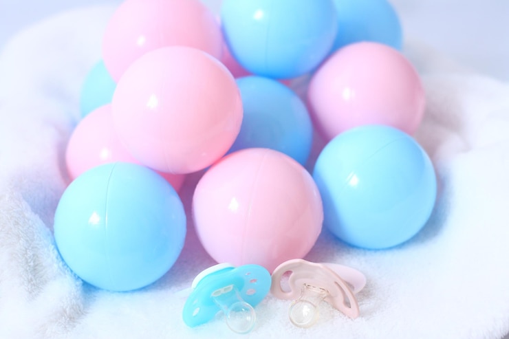 Photo gender reveal - is it a girl or a boy - pink and blue balls and pacifiers