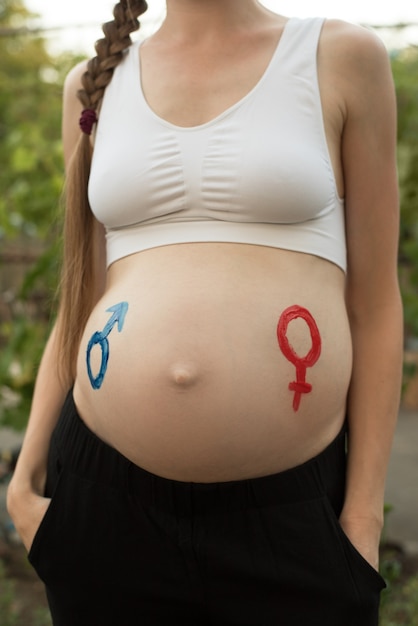 임신 한 여성의 배꼽에 그려진 성별 기호. 임신 개념. 확대