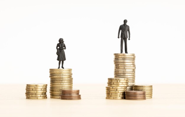 Photo gender wage gap concept man and woman figurines standing on top of the pile of coins copy space