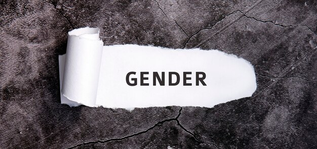 Gender wiht torn white paper on a gray concrete table.