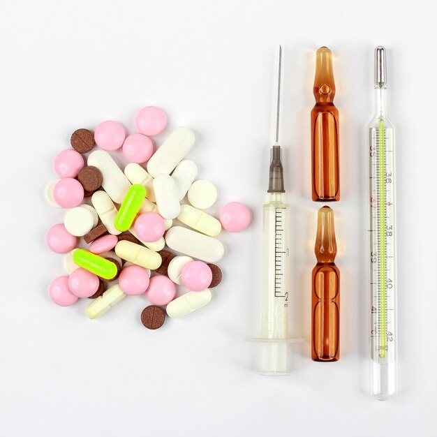 Geneeskrachtige tabletten, ampullen voor injecties, thermometer, spuit op witte achtergrond. farmacologie, geneeskunde en behandeling van ziekten