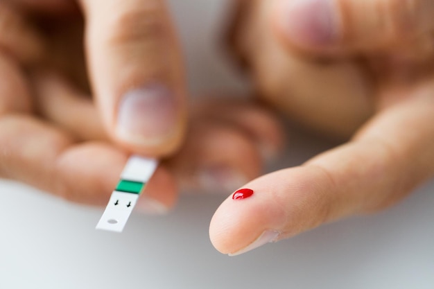 geneeskunde, diabetes, glycemie, gezondheidszorg en mensenconcept - close-up van mannelijke vinger met bloeddruppel en teststreep