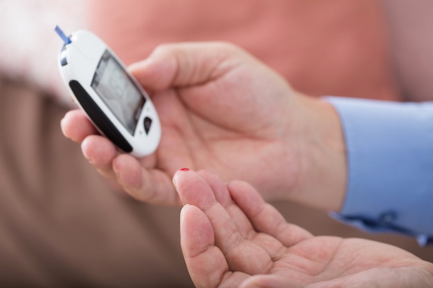 Geneeskunde, diabetes, glycemie, gezondheidszorg en mensenconcept - sluit omhoog van mannelijke vinger met teststreep