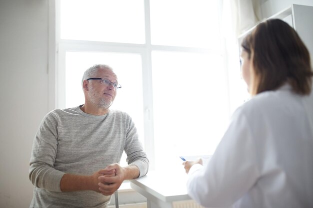 geneeskunde, leeftijd, gezondheidszorg en mensenconcept - senior man en arts ontmoeten elkaar in medisch kantoor in het ziekenhuis