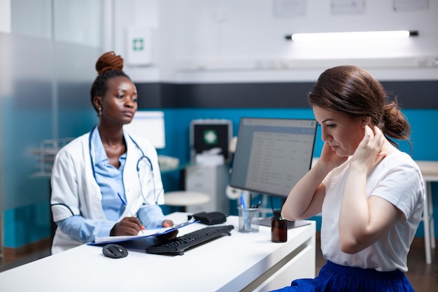 General practitioner doctor consulting patient with sore, hurt, aching painful neck nape symptoms. Healthcare specialist medical appointment check-up in modern clinic office