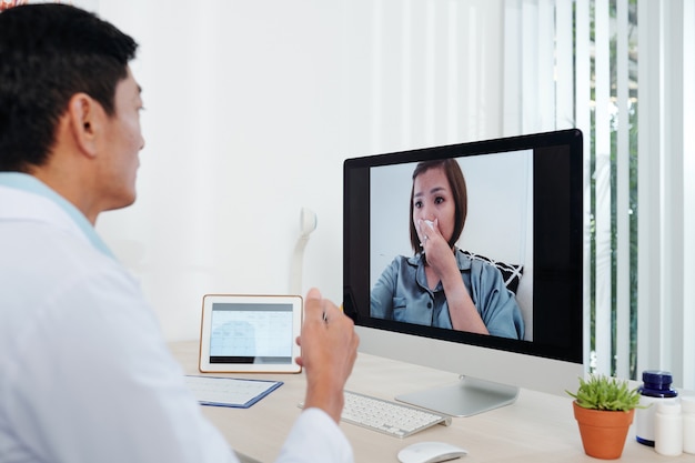 General practitioner having video call with crying frightened female patient