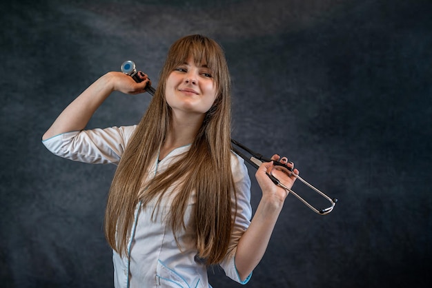 Photo general practitioner internt in white coat with stethoscope at studio against gray background