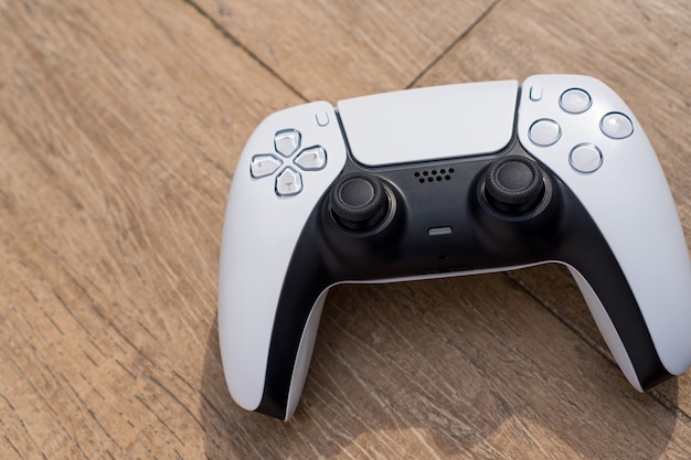 Next generation white game controller isolated on wooden background. Natural light. Selective focus.