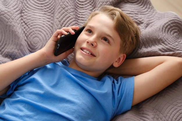 Generation Z boy talking on the phone while lying on his bed at home