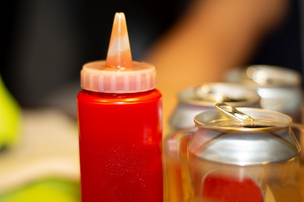 Generic jar of hamburger ketchup next to soda cans