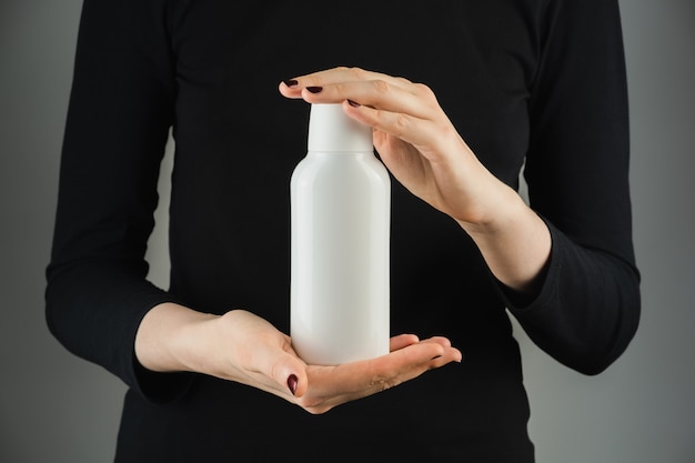 Photo generic white bottle in female hands on gray