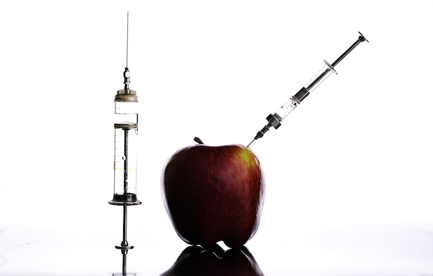 Genetically modified foods, apple pumped with chemicals from a syringe