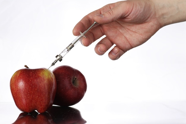 Genetically modified foods, apple pumped with chemicals from a syringe
